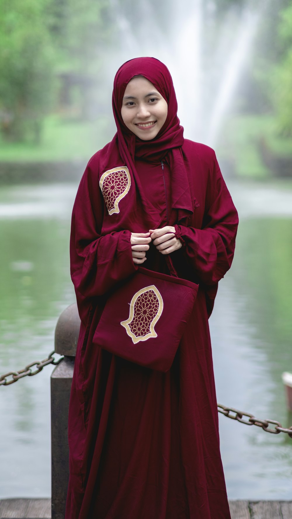 woman in red hijab standing near body of water during daytime