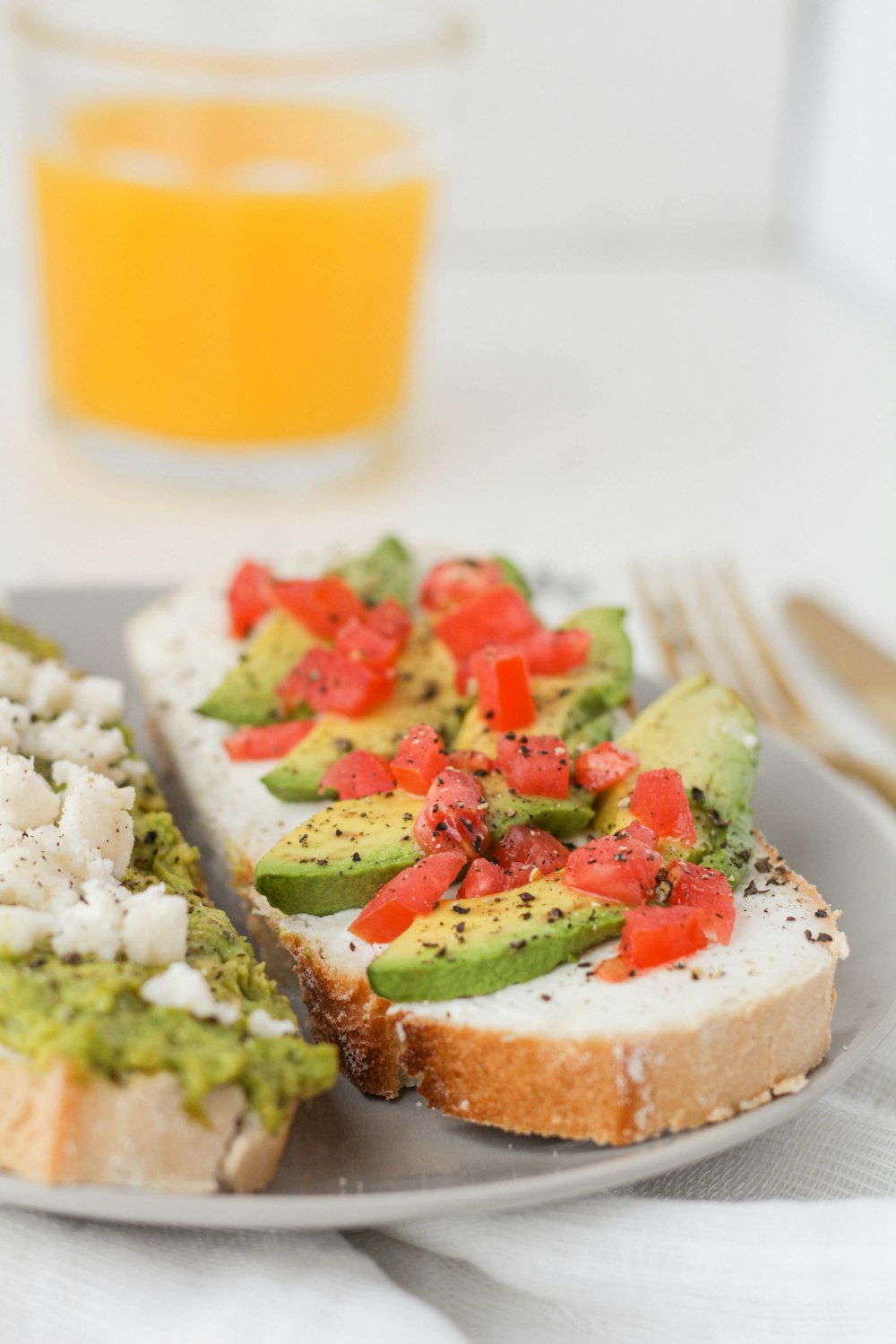 sliced bread with sliced tomato and green leaf vegetable on white ceramic plate