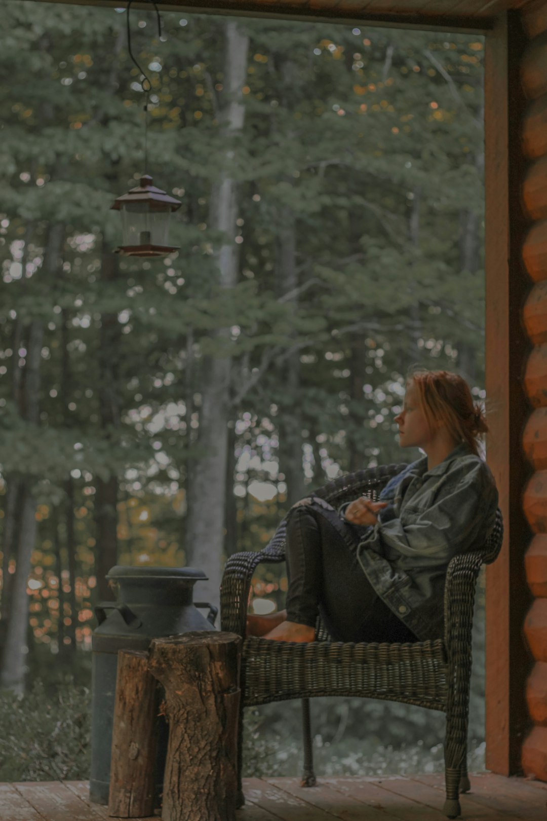 woman in black and gray jacket sitting on brown wicker armchair