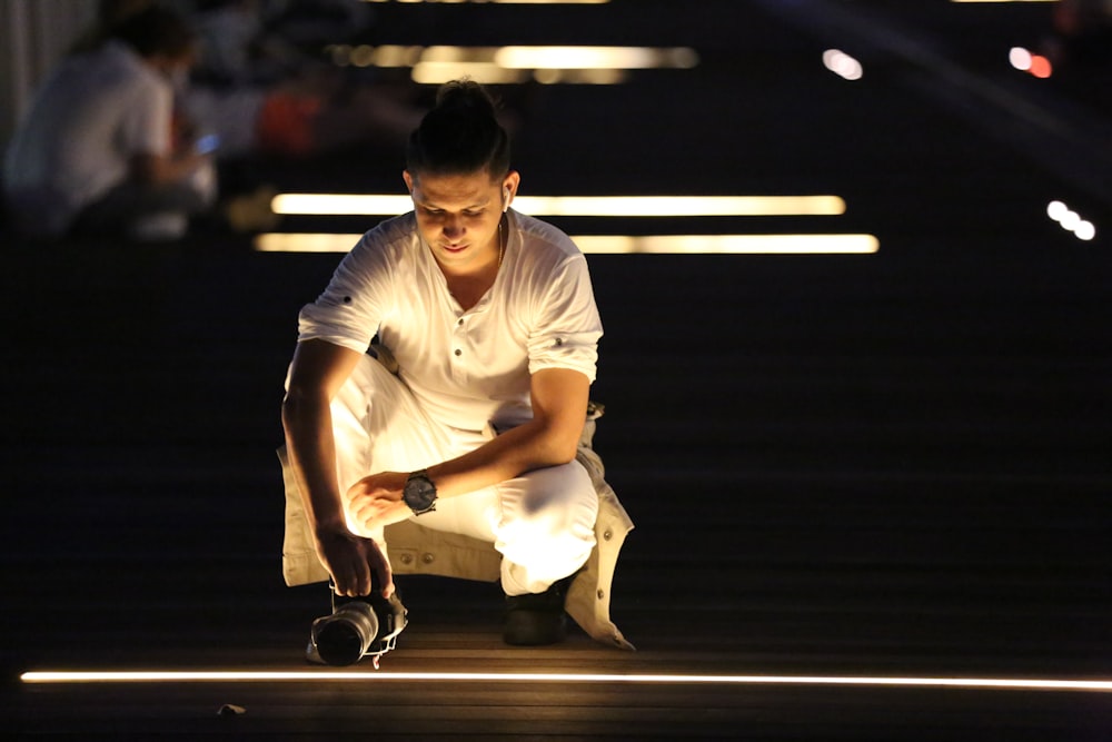 uomo in polo bianca e pantaloncini bianchi seduto sullo skateboard nero