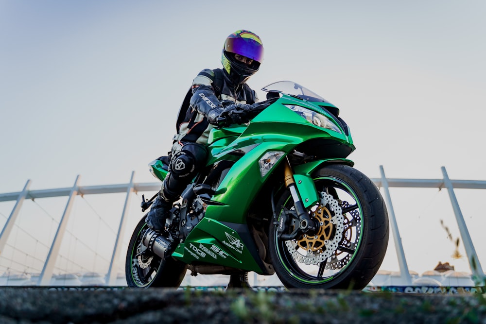 man in green and black motorcycle suit riding on green and black sports bike