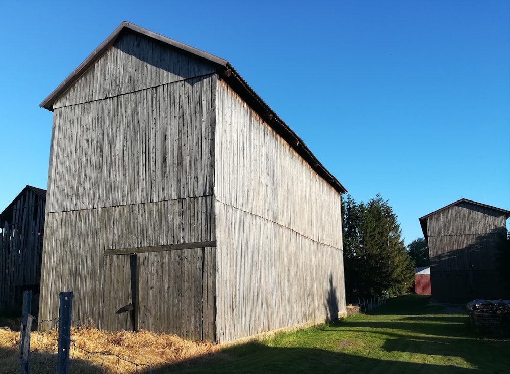 brown wooden barn on green grass field under blue sky during daytime