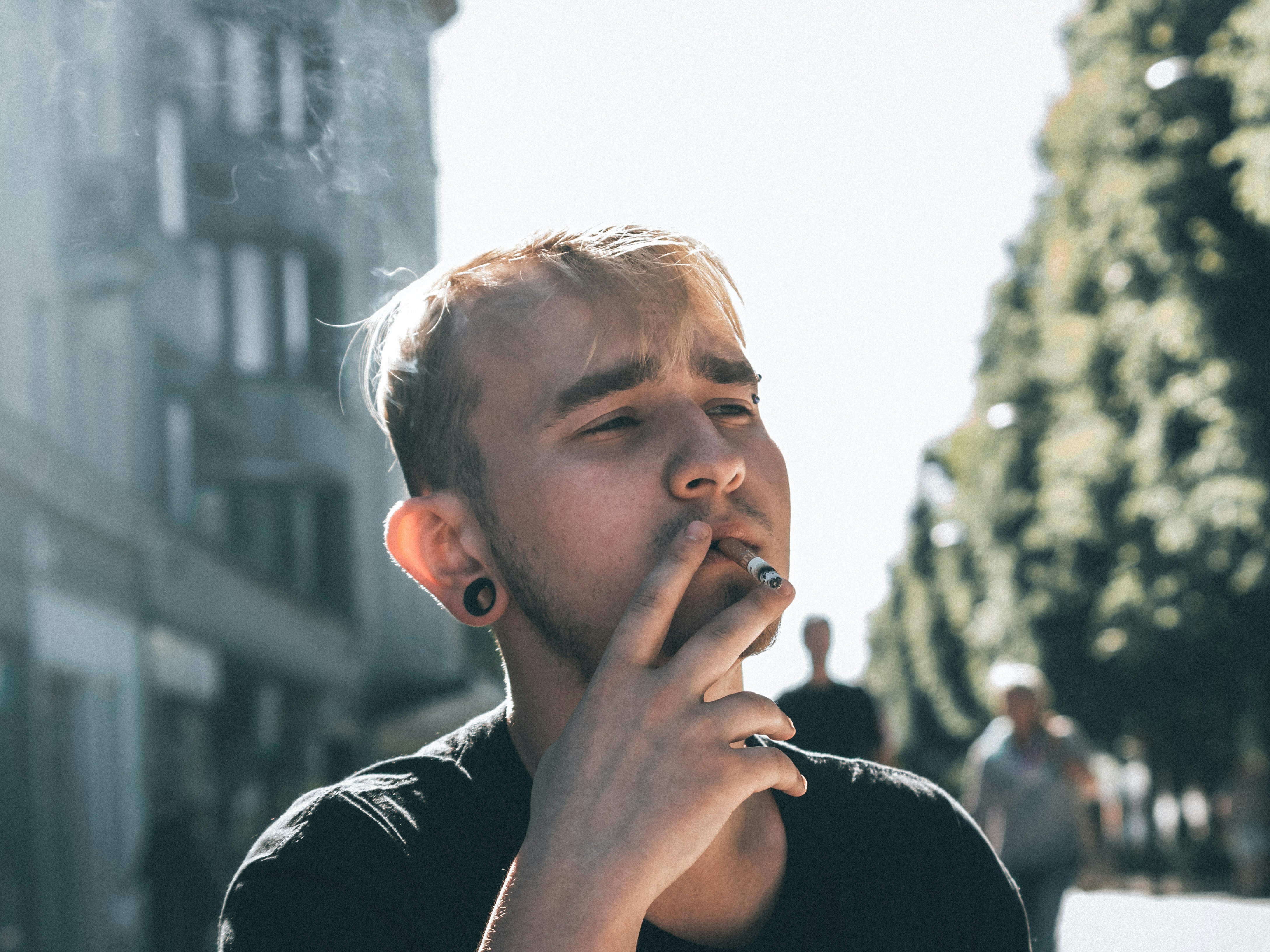 man in black crew neck shirt smoking cigarette during daytime