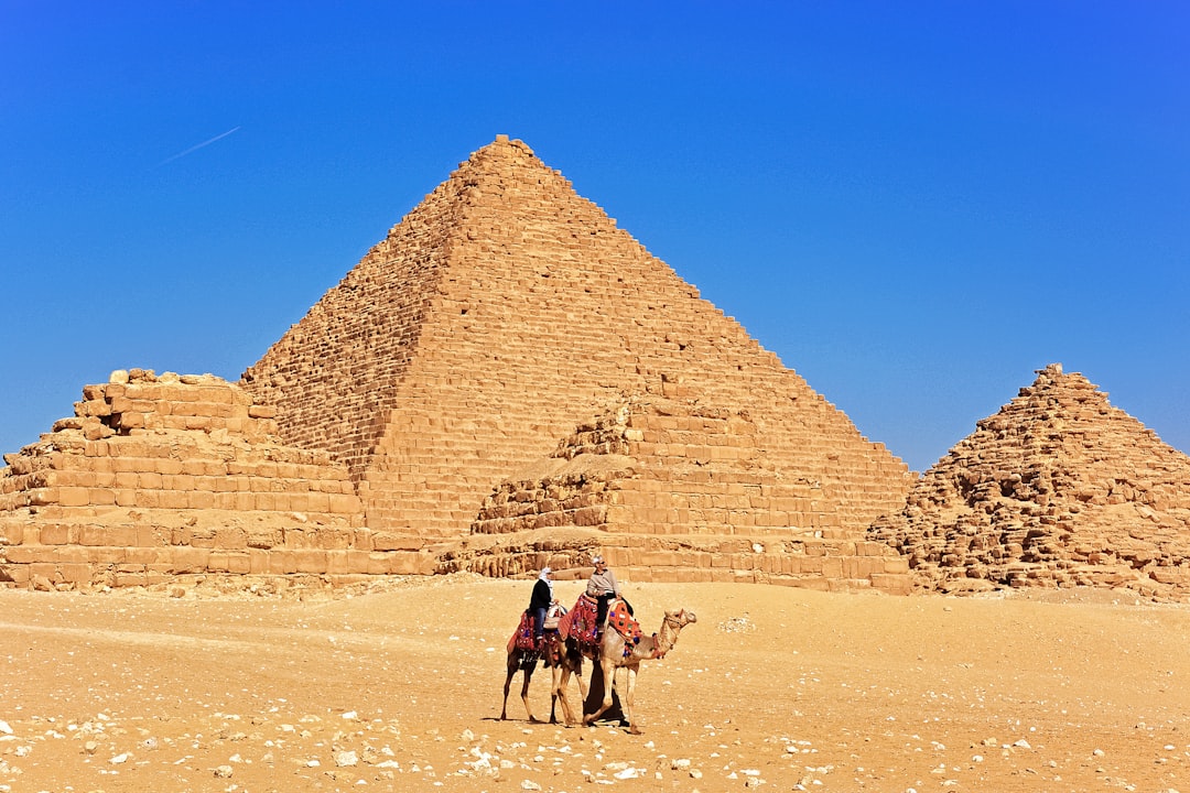 people walking on sand near pyramid during daytime