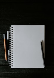 white spiral notebook beside orange pen