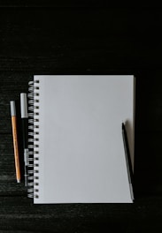 white spiral notebook beside orange pen