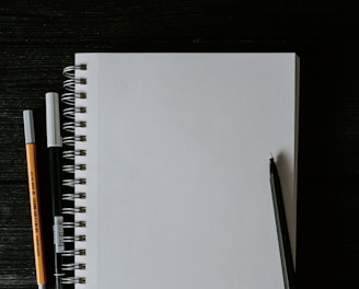 white spiral notebook beside orange pen