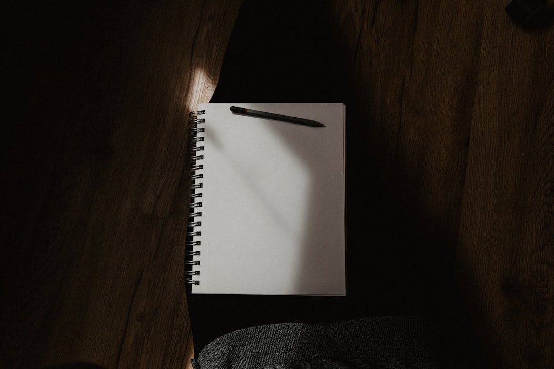 white spiral notebook on black textile