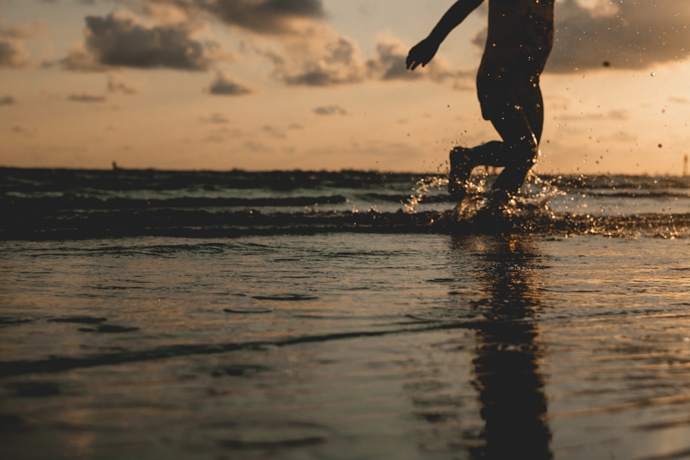 夕暮れ時の水の上を歩く人のシルエット