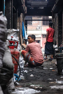 man in orange long sleeve shirt sitting on gray concrete floor