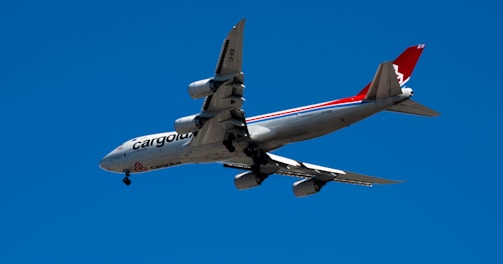 white and red airplane in mid air during daytime