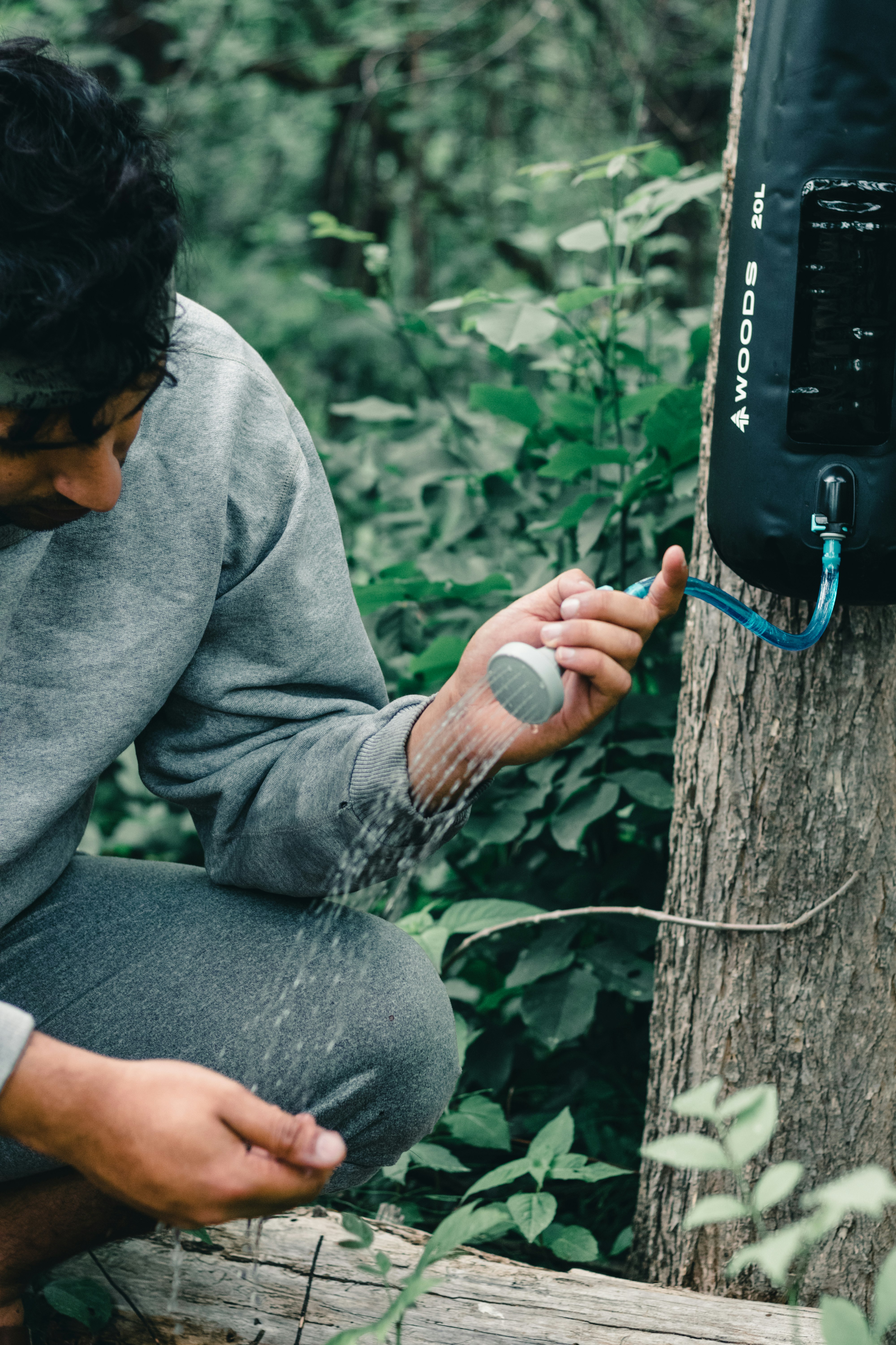 man in gray sweater and gray pants sitting on brown tree trunk