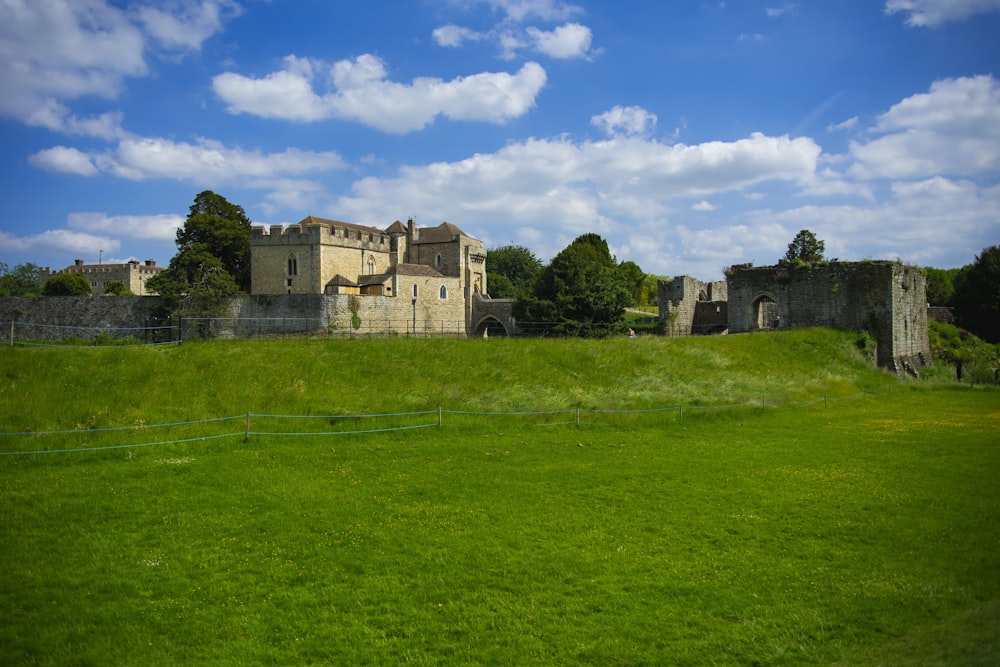 green grass field near brown concrete building under blue sky during daytime