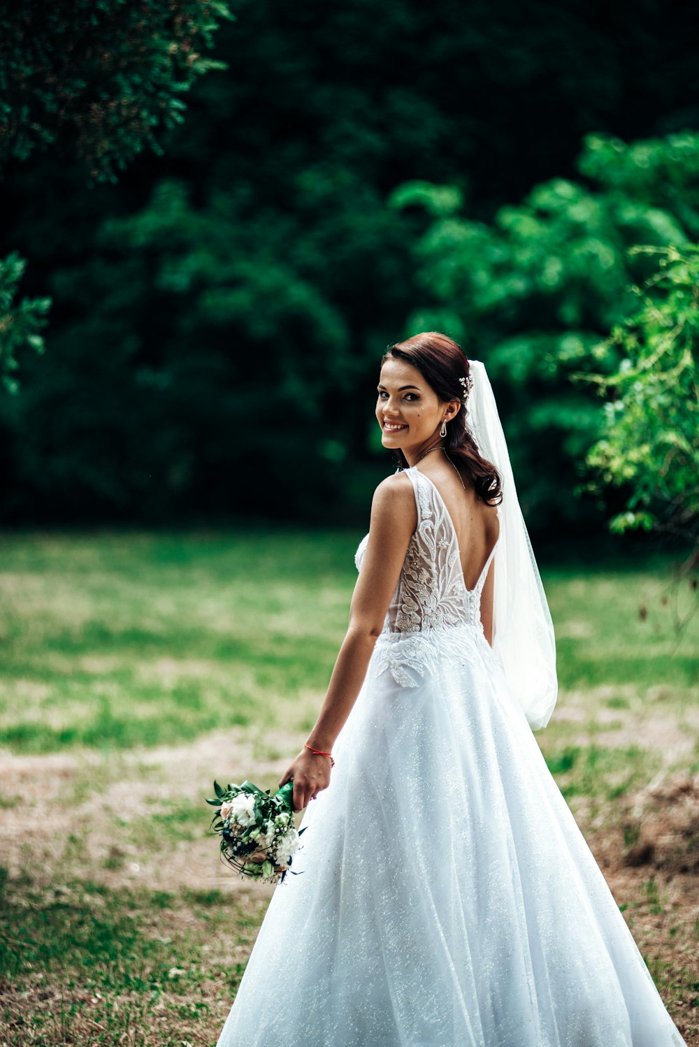 woman in white sleeveless dress holding bouquet of flowers