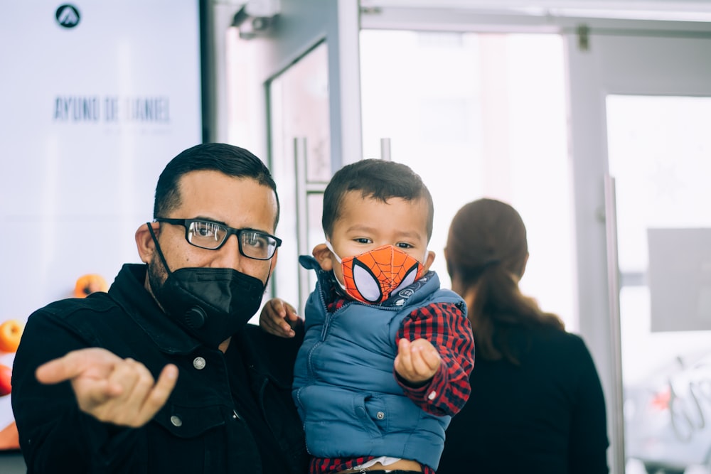 赤と黒の市松模様のジャケットを着た男の子を運ぶ黒いジャケットの男