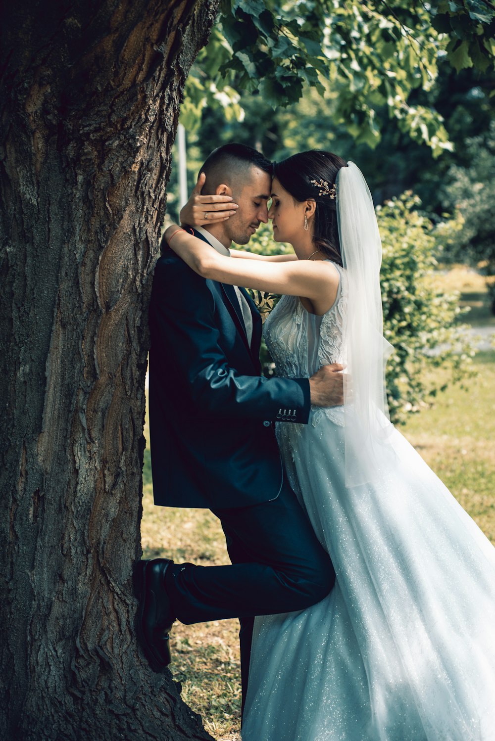 man and woman kissing beside brown tree during daytime