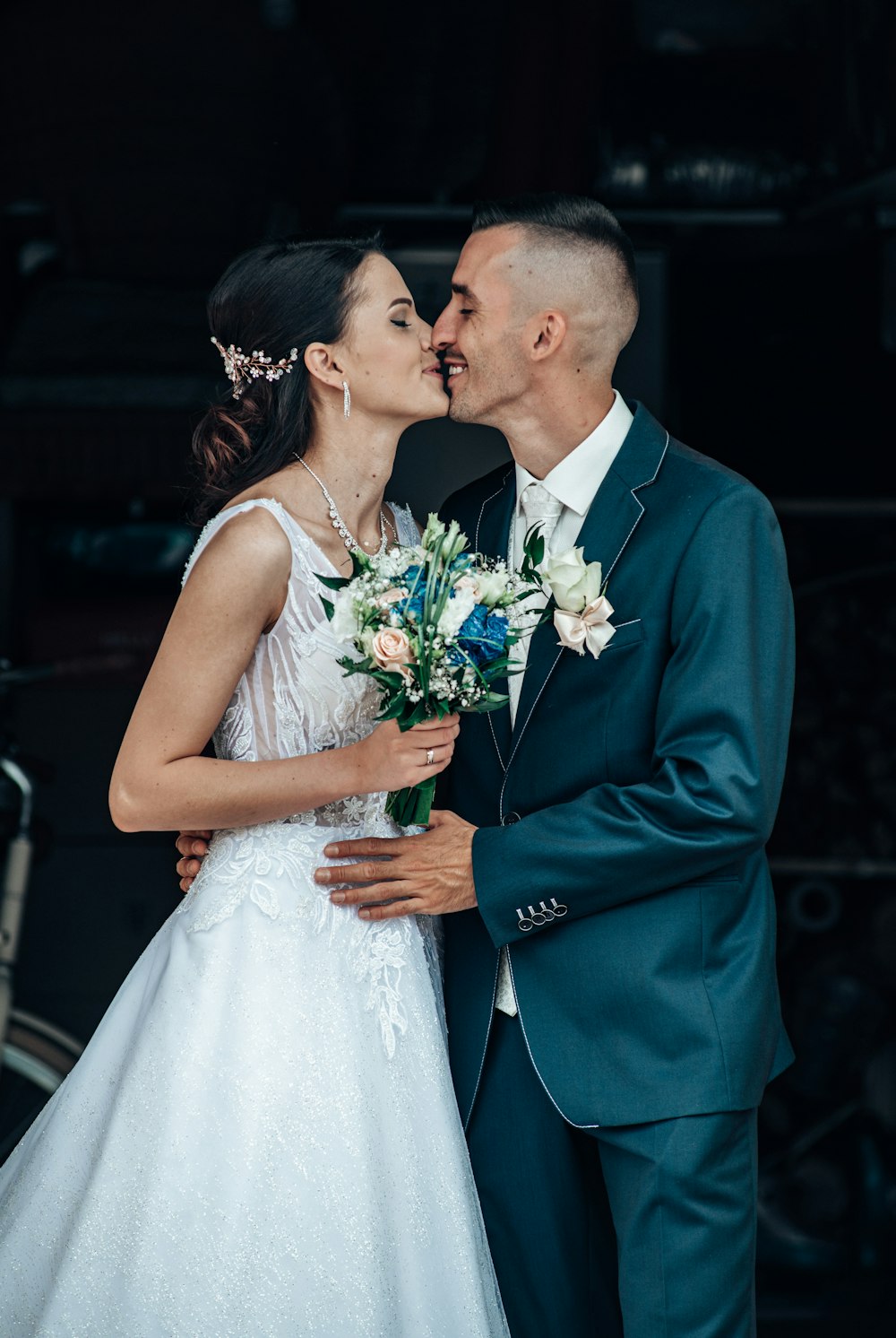 man in blue suit kissing woman in white wedding dress