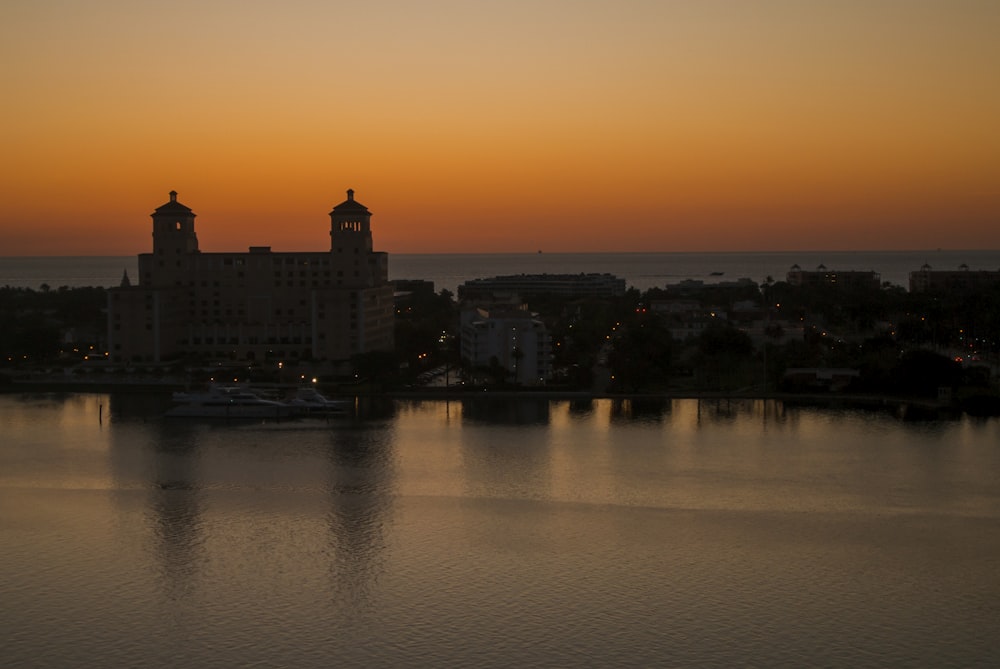 silhouette di edificio vicino allo specchio d'acqua durante il tramonto