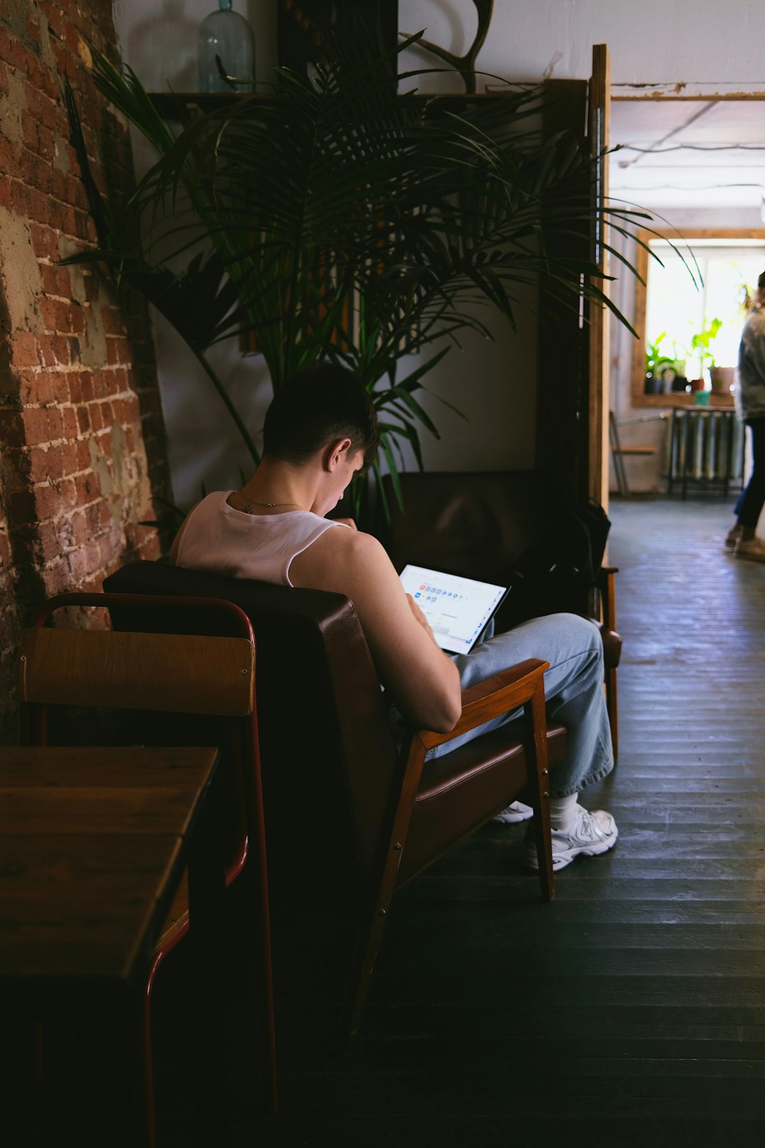 woman in white tank top sitting on brown wooden armchair