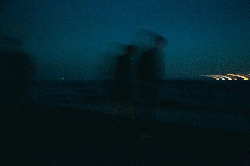 silhouette di persona in piedi sulla spiaggia durante la notte