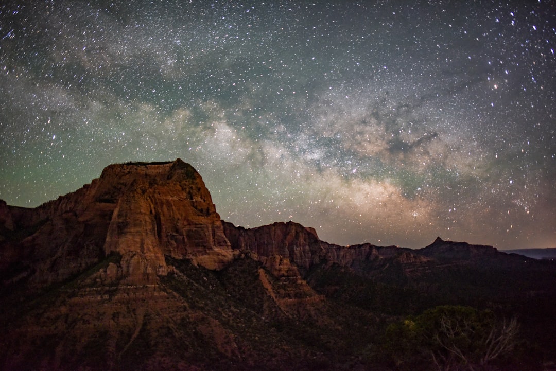 brown rocky mountain under blue sky with stars during night time