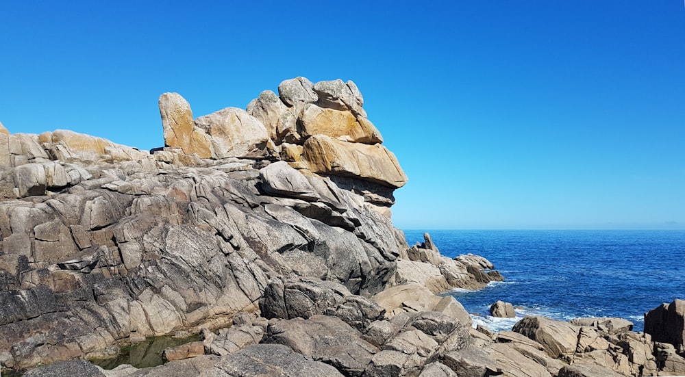 brown rock formation near body of water during daytime