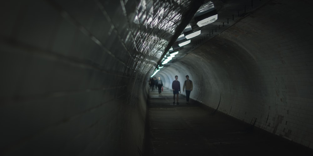 2 person walking on tunnel
