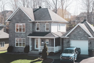 black car parked in front of brown and white house