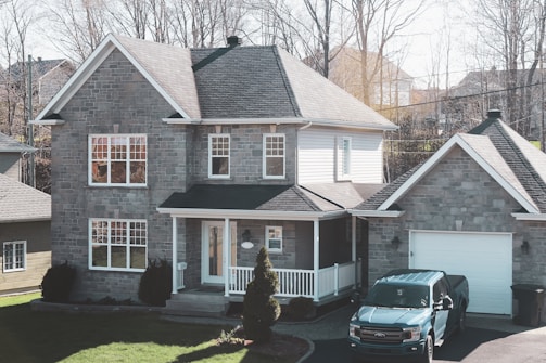 black car parked in front of brown and white house
