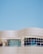 A modern architectural structure with smooth, curved lines and large, reflective windows. The building facade features a sleek, white grid design against a clear blue sky, creating a sense of openness and innovation.