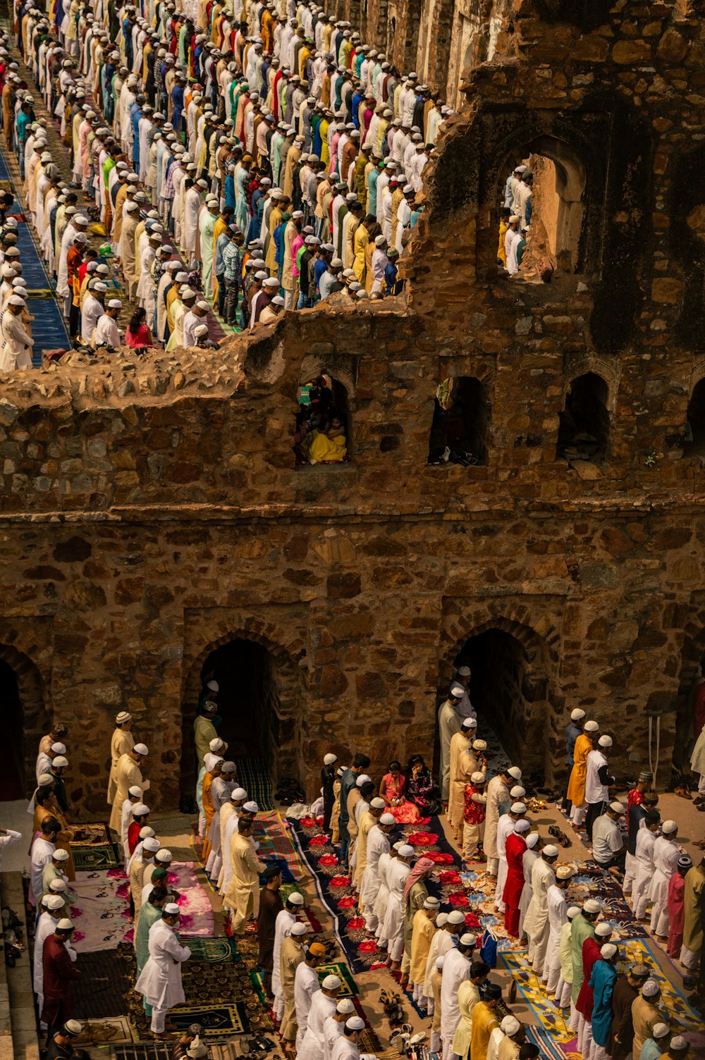 Personas vestidas con trajes tradicionales de pie sobre un edificio de hormigón marrón durante el día