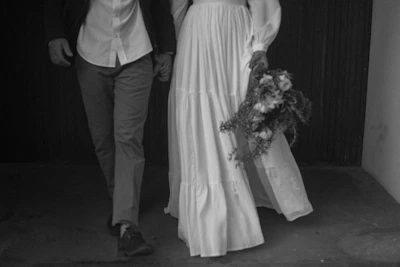 An elegant black and white photo of a couple holding hands with colorful confetti falling around them.