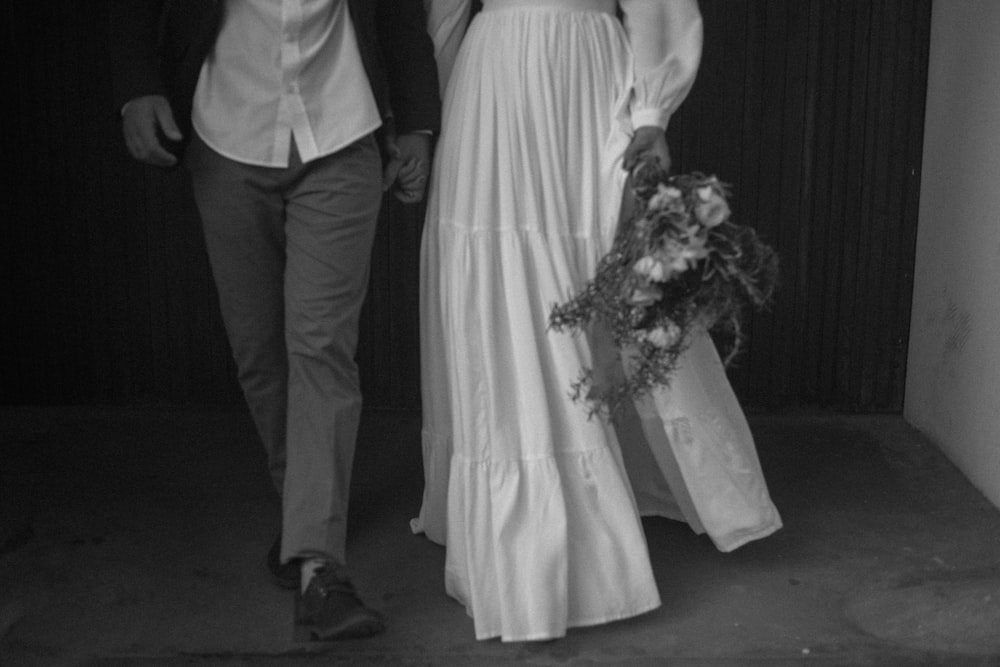 grayscale photo of man and woman holding hands