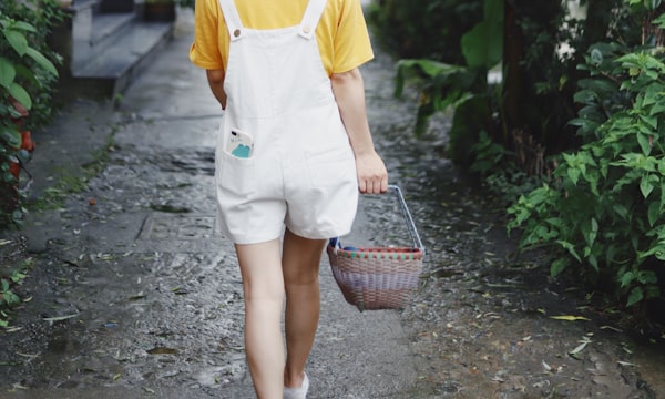 woman in white and yellow shirt walking on pathway