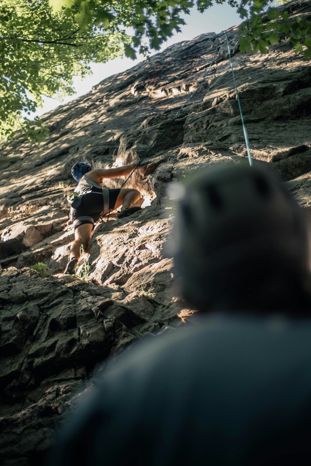 man in black t-shirt and brown shorts climbing on rocky mountain during daytime