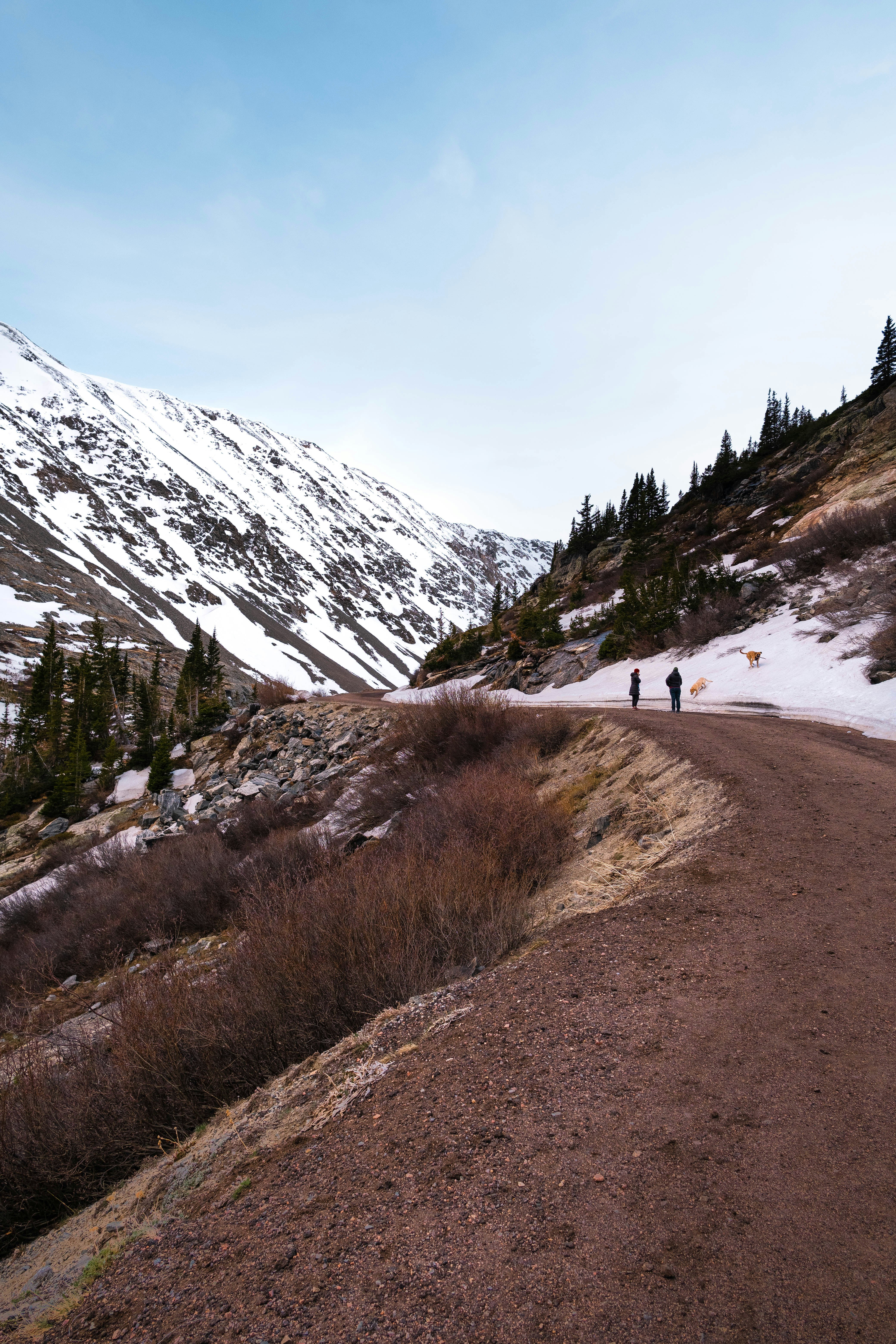 person walking on dirt road near snow covered mountain during daytime
