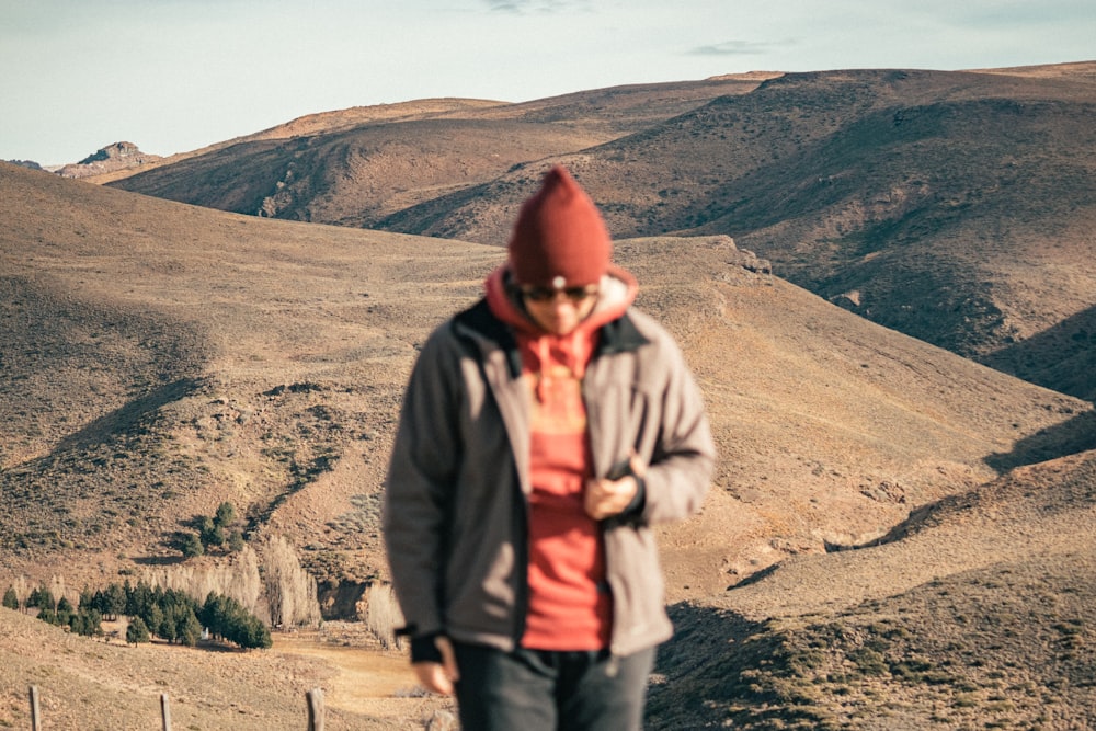 man in gray jacket standing on brown sand during daytime