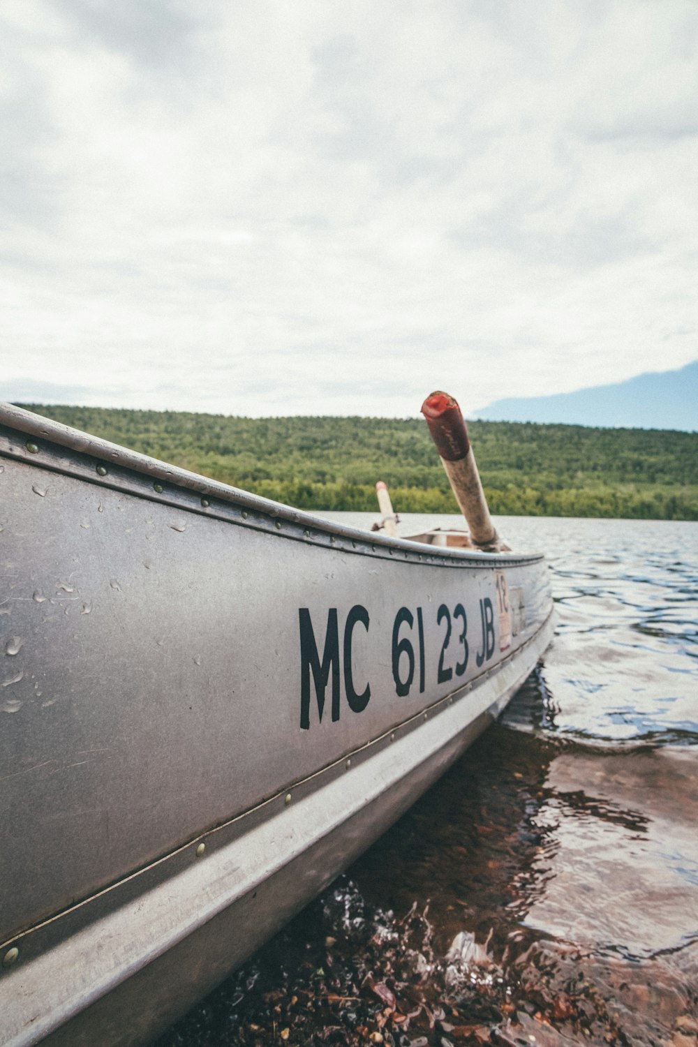 man in red shirt and black pants sitting on gray boat on body of water during