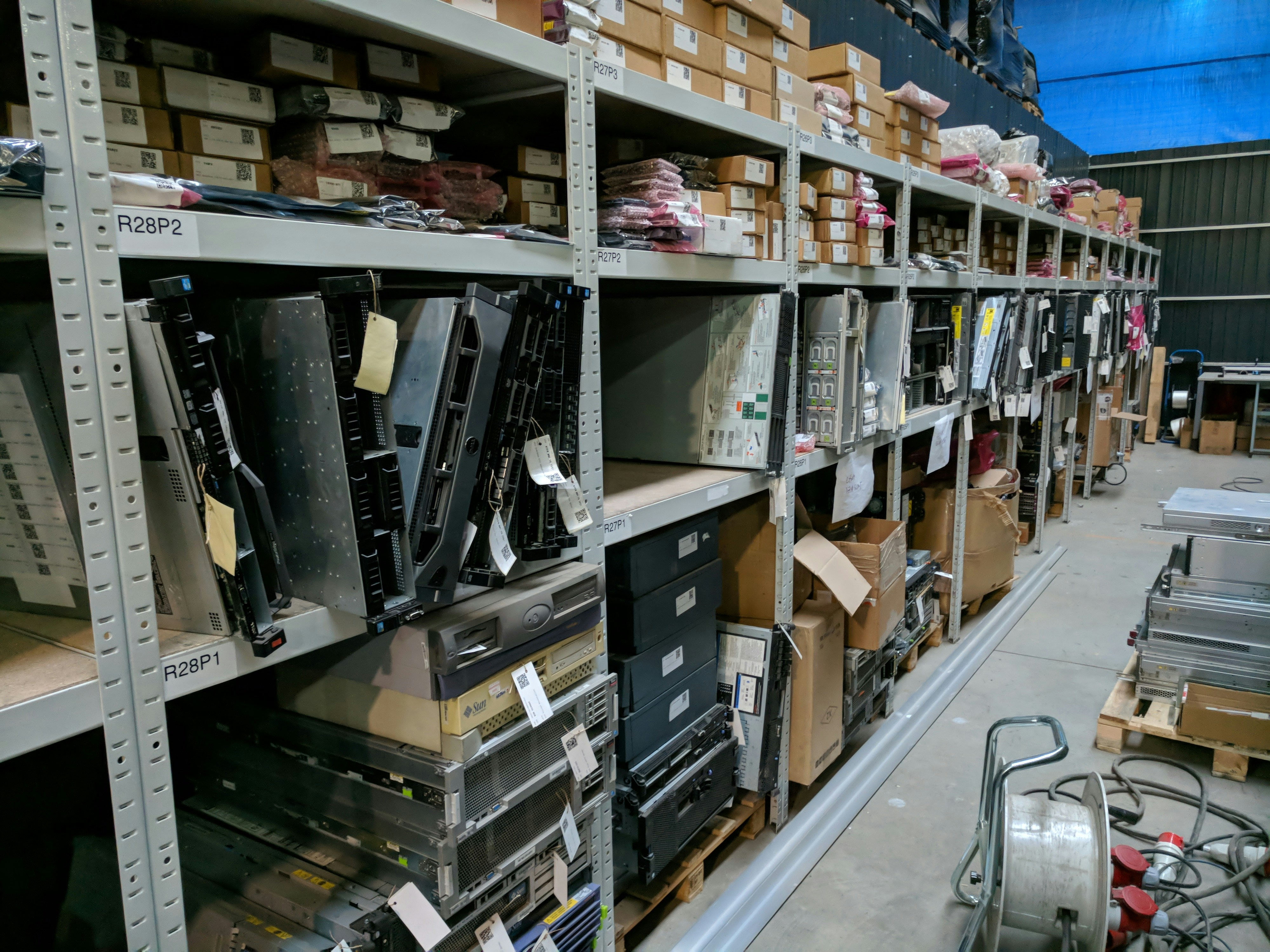 Modern warehouse facility with organized rows of refurbished computer equipment and servers on industrial shelving