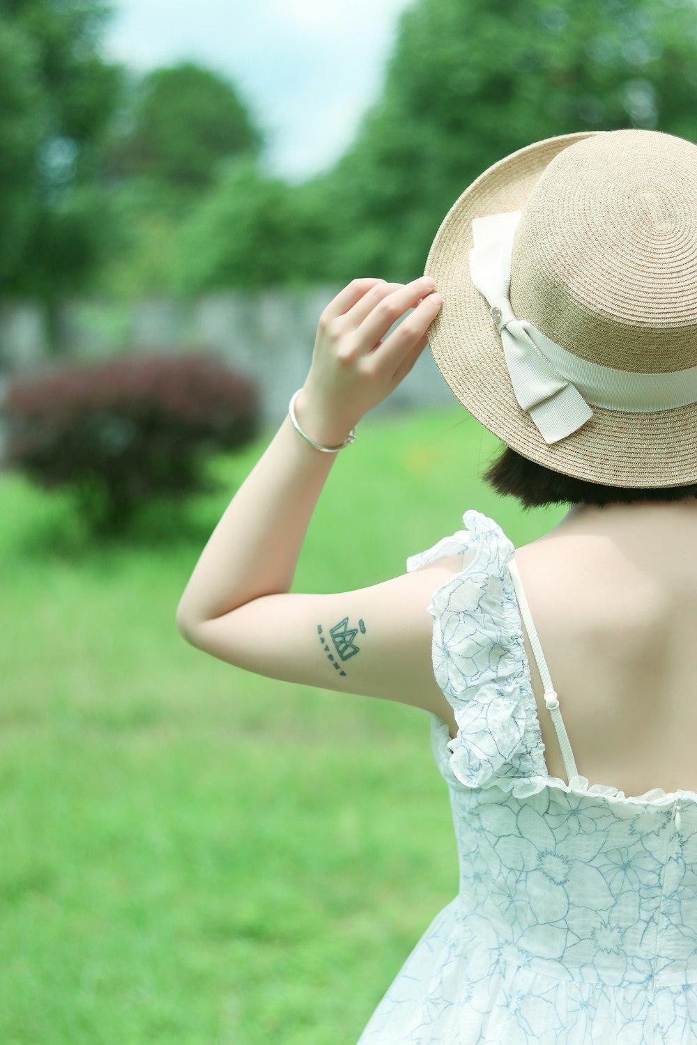 woman in white floral lace dress wearing brown hat