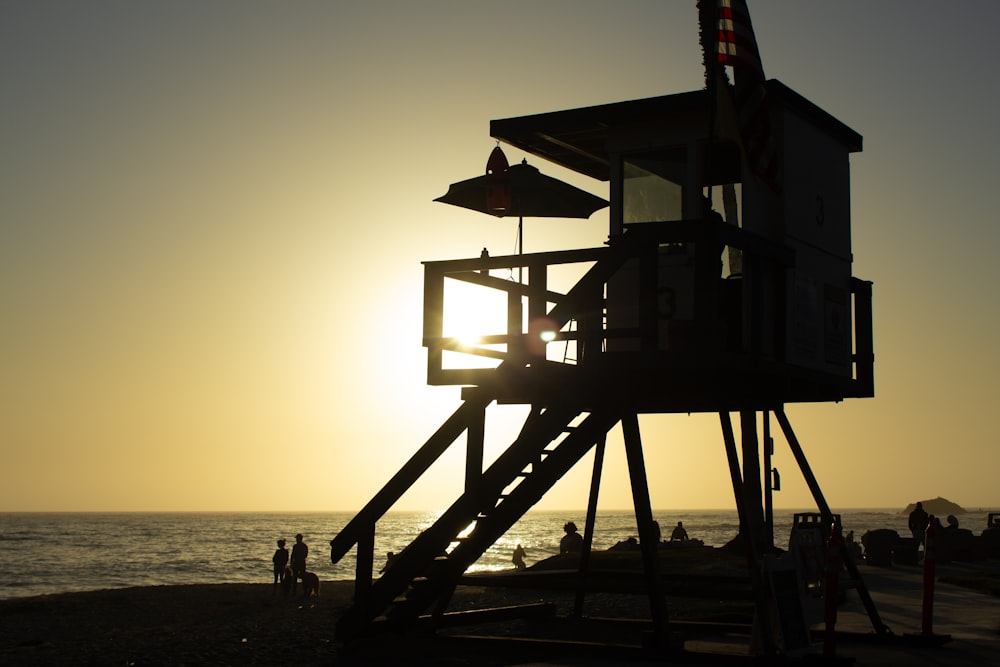 silhouette of lifeguard tower on beach during sunset