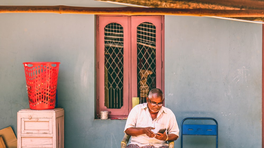 man in white button up shirt sitting on chair near blue door