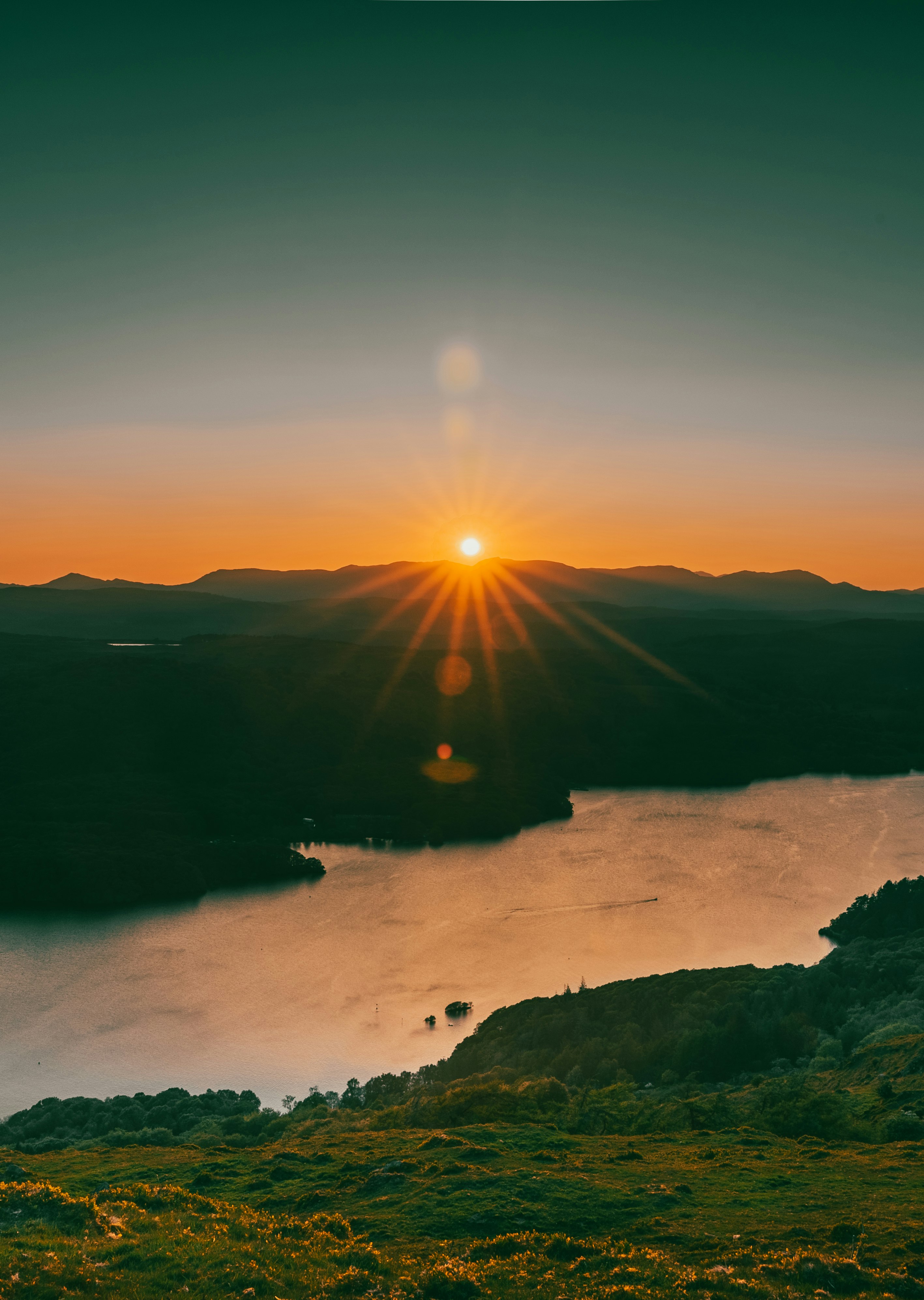 sun setting over the mountains and body of water