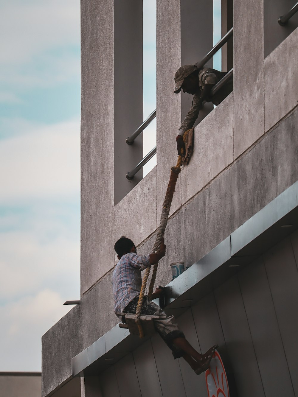 man in blue denim jeans and black shoes climbing on gray concrete wall during daytime