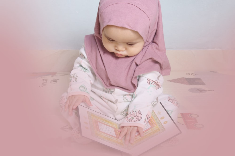 Bebé con hiyab rosa y camisa blanca de manga larga