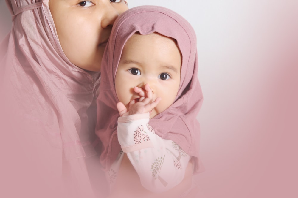 baby in pink hijab and white floral long sleeve shirt