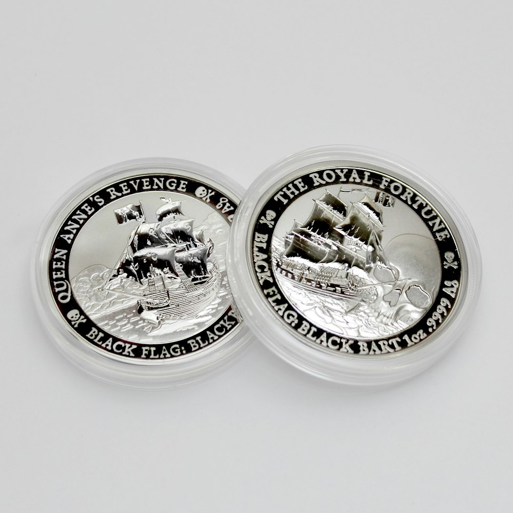 2 round silver coins on white surface