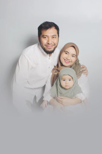 man in white dress shirt carrying girl in green dress