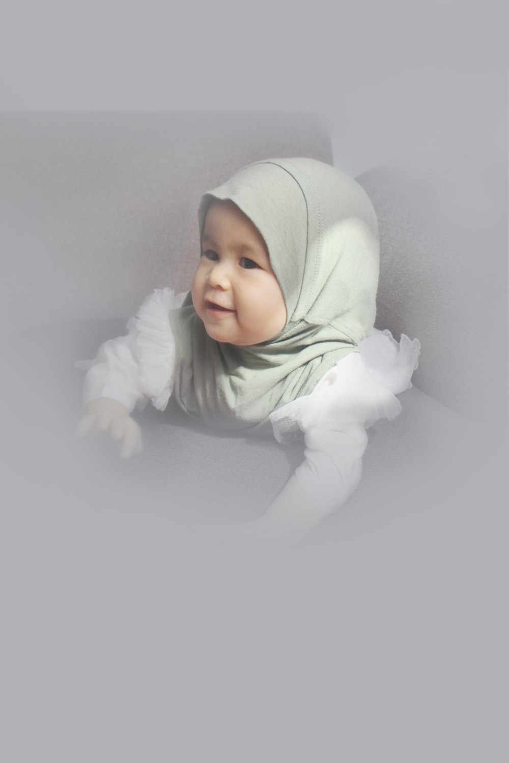 baby in white hoodie lying on white bed