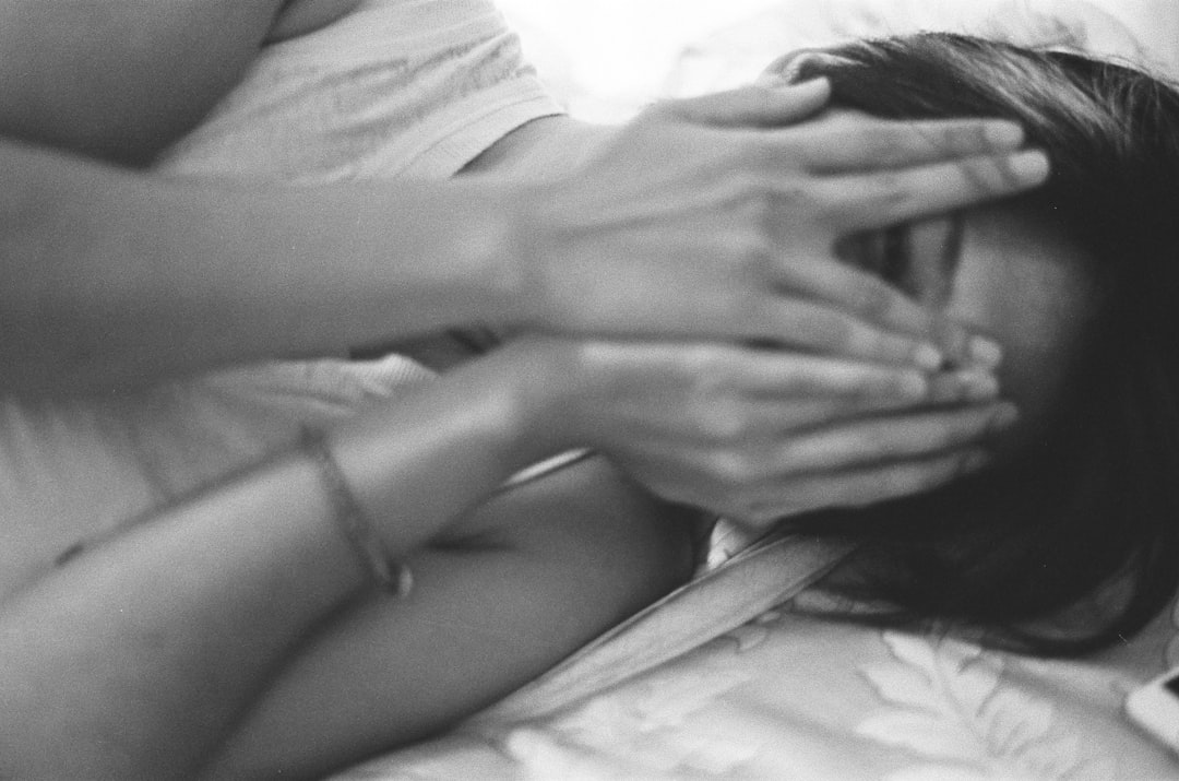 grayscale photo of woman in white shirt covering face with hands